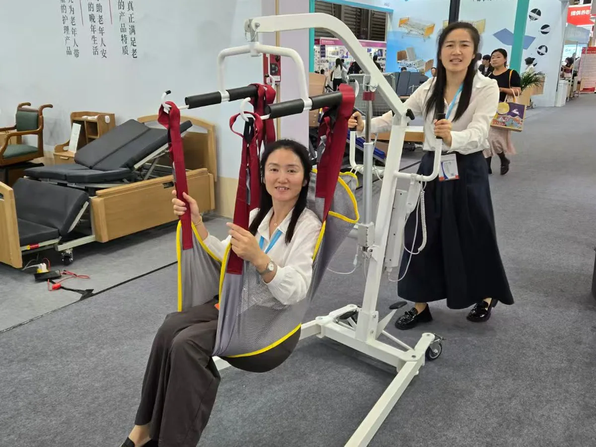Hands-on demonstration of the SL-K11 mobile patient hoist with sling at a healthcare exhibition